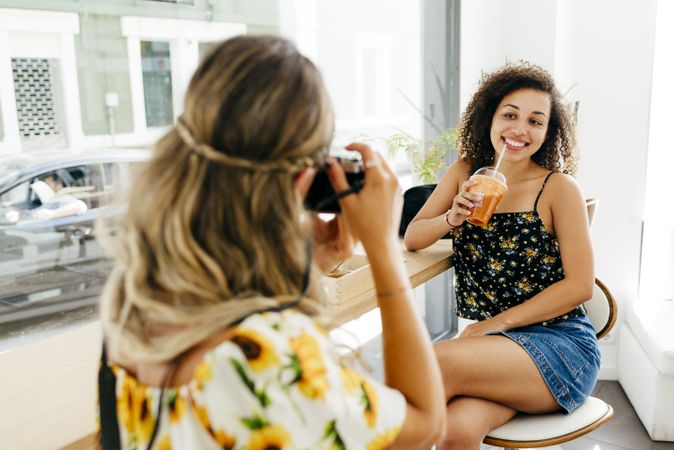 Woman taking photo of friend in cafe