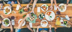 Top view of group of people at restaurant with wooden table and gastropub type food