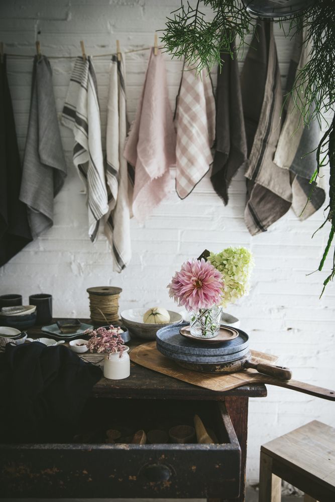 Table with flowers in vase on trays near towels hanging on thread