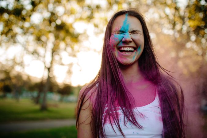 Cheerful girl at park with colored powder on her face