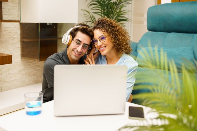 Happy couple using laptop on coffee table at home