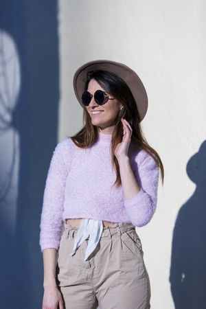 Front view of smiling young woman wearing sunglasses and hat