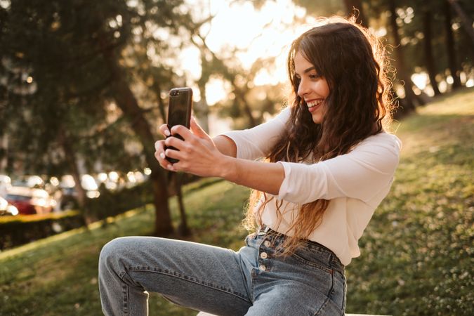 Cheerful woman taking selfie in park