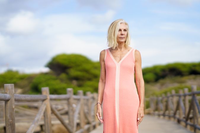 Mature woman with grey hair standing on wooden walkway near the coast