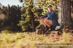 Portrait of an older man sitting outdoors in forest with a compass 0WXVP5