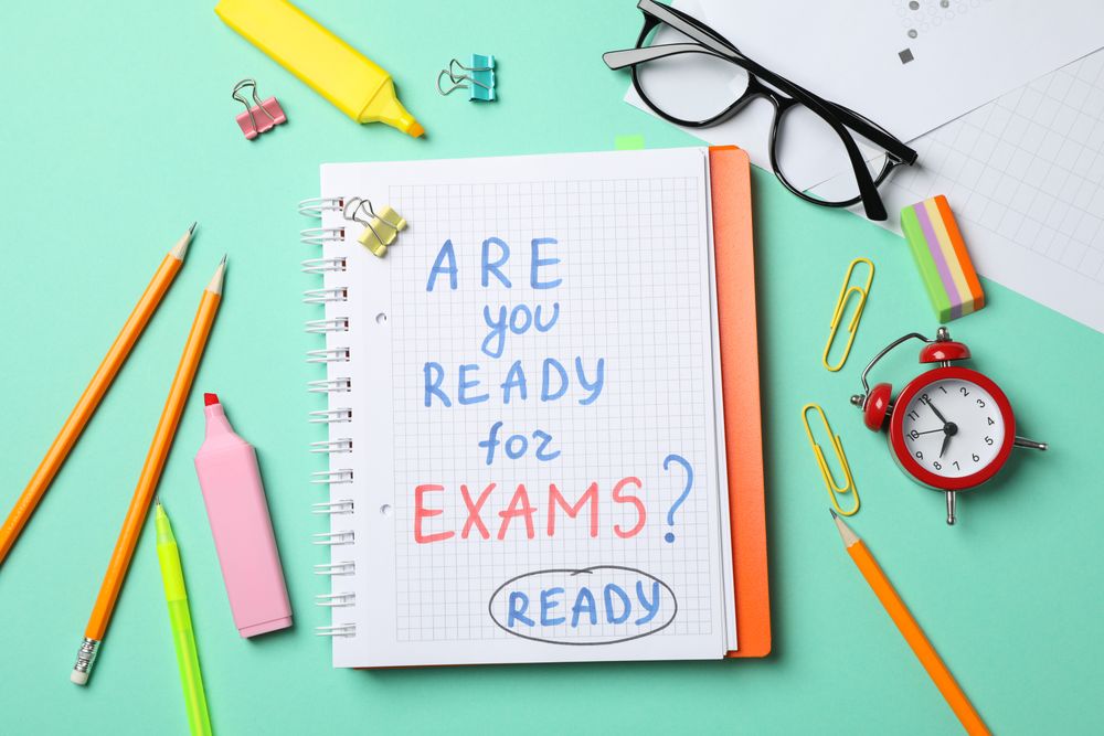 Looking down of pens, pencils and open notebook with the words “Are you ready for exams”