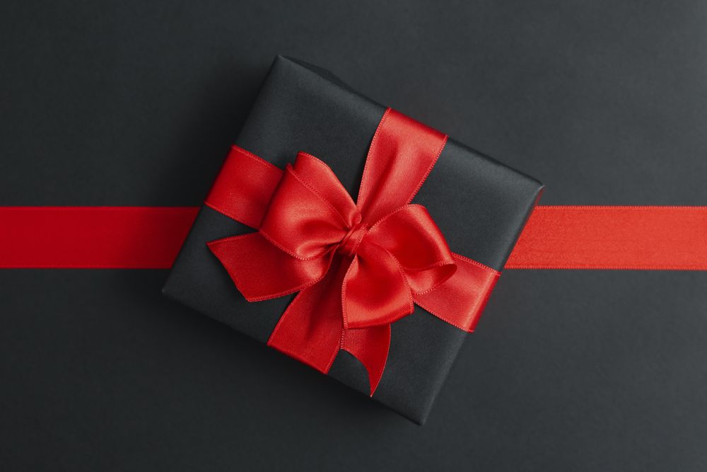 Gift box and red ribbon on dark background