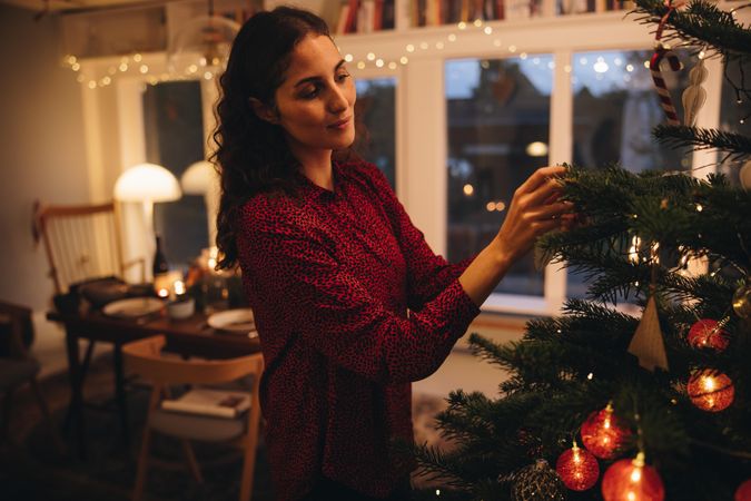 Female decorating Christmas tree at cozy house