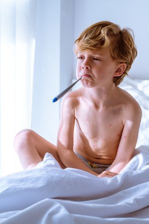Sick boy measuring temperature in mouth