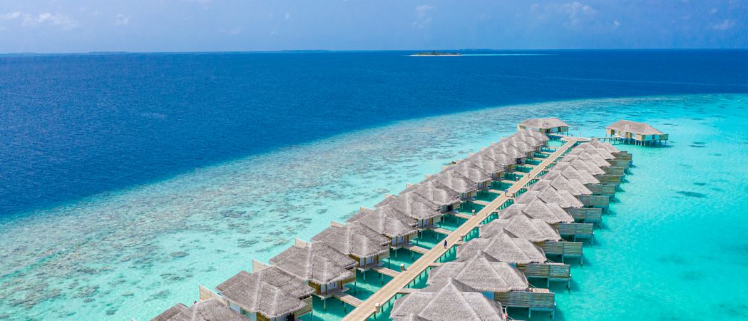 Two rows of overwater bungalows at a beach resort