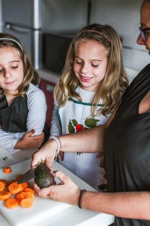 Anonymous adult preparing vegetables for salad with kids