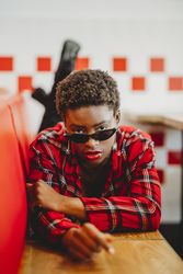 Gorgeous stylish Black woman in sunglasses in cafe