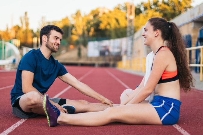 Two athletes stretching after an athletics training session.