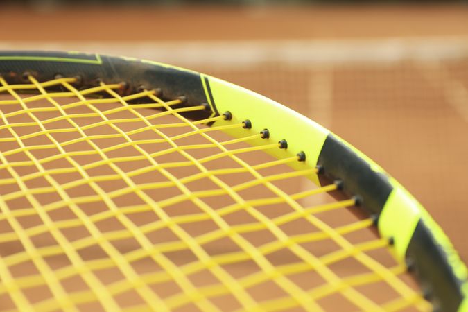Tennis racquet against clay court, close up