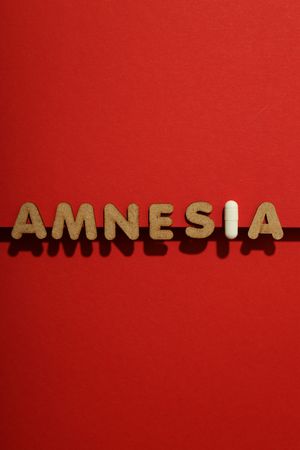 Cork letters of the word “Amnesia” with pill, in center of vertical composition