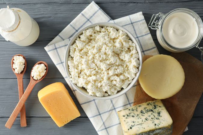 Different dairy products and towel on grey wooden background, top view