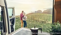Couple enjoying beautiful morning view outside of camper van with cup of coffee 0LG2Vb