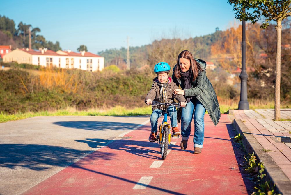 Woman helping boy to ride his bike