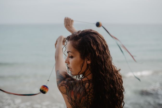 Tattooed woman dancing with balls near sea