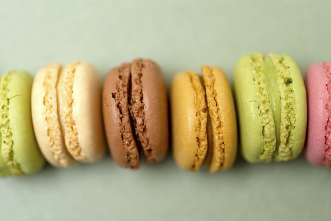 Line of colorful tasty macaroons over a green table