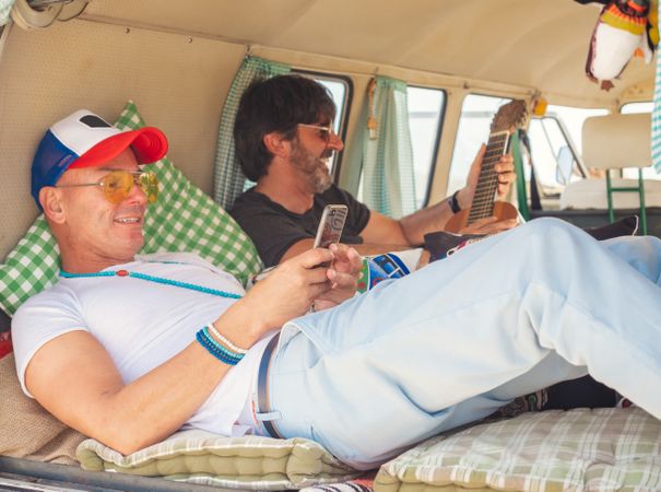 Men relaxing with mobile phones in van