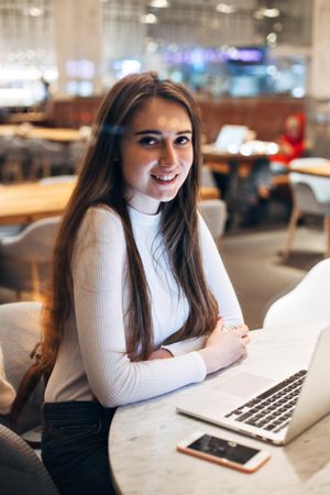 Young brunette woman smiling while working on her laptop