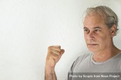 Portrait of middle aged man in gray shirt holding a fist 0P23e4