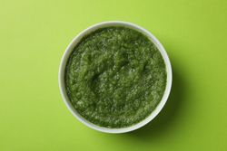 Top view of bowl of broccoli soup on green table