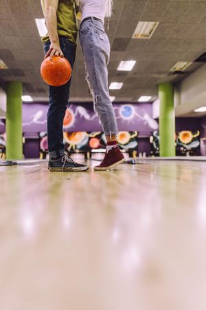 Legs of man and woman with ball at bowling alley