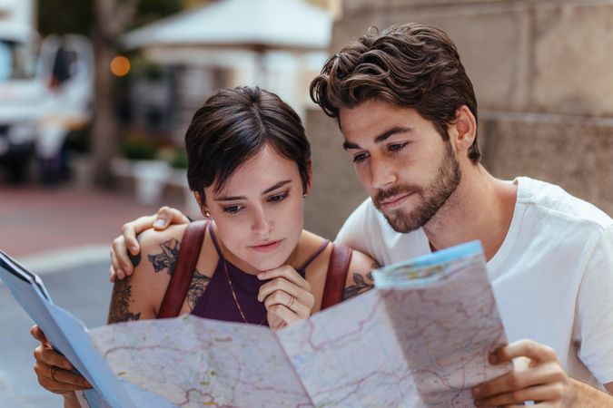 Tourist couple using a map to find the route to their destination