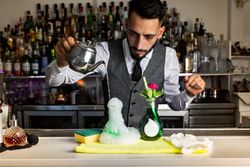 Bartender pouring hot liquid from a pitcher to a special cocktail