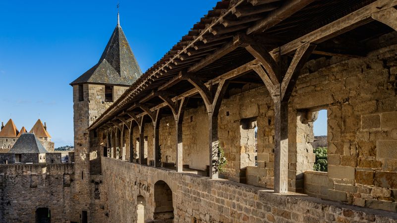 Corridor over the courtyard Cour Du Midi fortified castle in Carcassonne. France. A long, narrow stone building with a tower on top