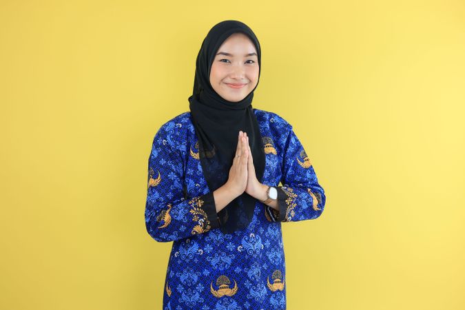 Female ASN Wearing Korpri Batik Gesturing Greeting Namaste