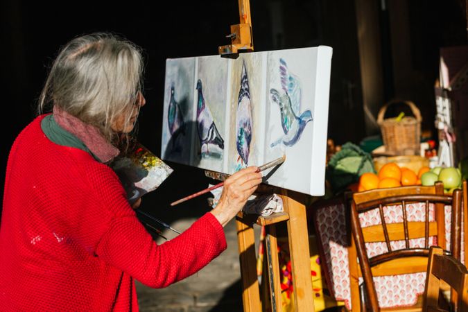 Mature woman painting on canvas in garden