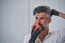 Mature man putting on protective mask from coronavirus pandemic