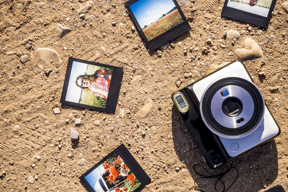 Stylish accessories and instant photos on sandy ground