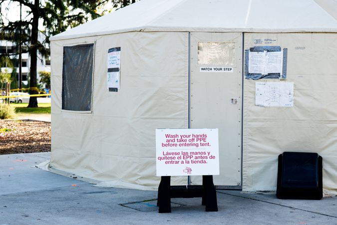 Sign with safety instructions in front of testing tent for medical workers at Covid testing site