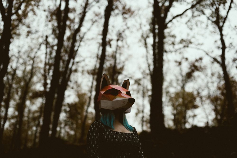 Woman in red fox mask walking in forest