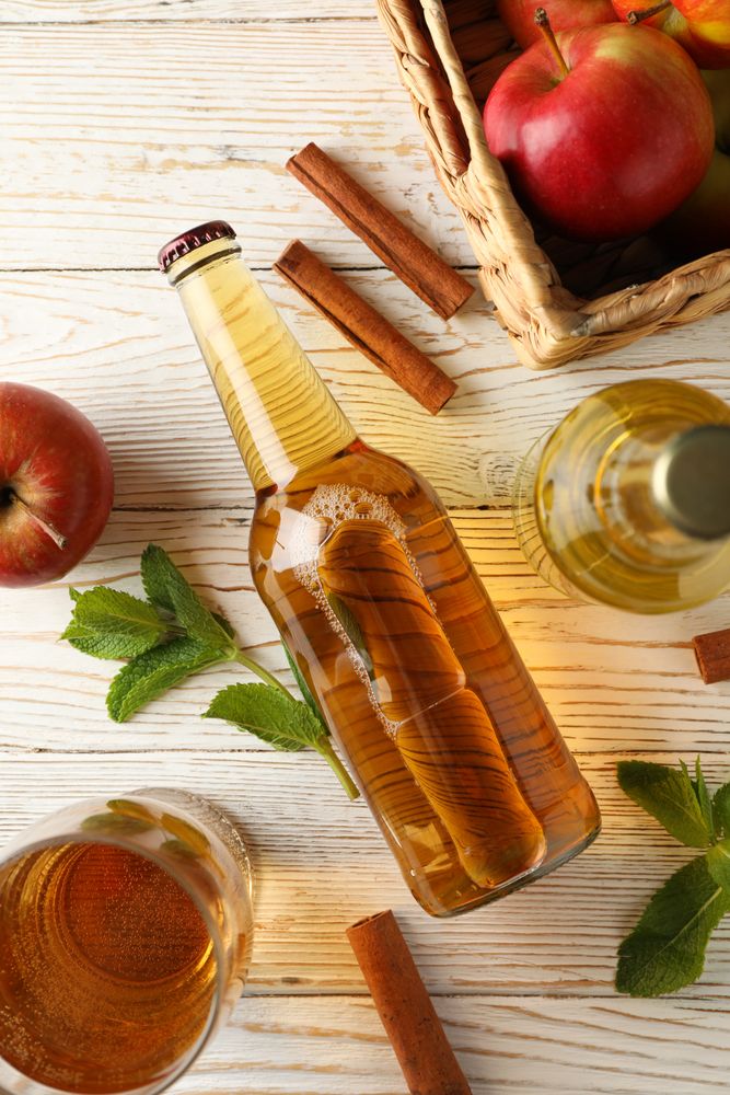 Composition with cider, cinnamon and apples on wooden background
