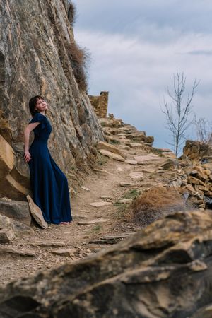 Woman in long blue dress standing on mountainous pathway in Hamsutl, Dagestan