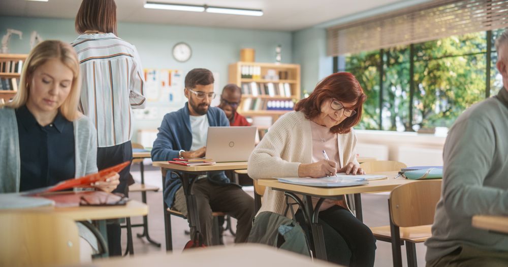 Diverse Mature Students Learning in Classroom, Using Laptops and Writing in Notebooks.