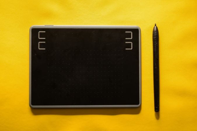 Digital tablet and stylus on yellow table