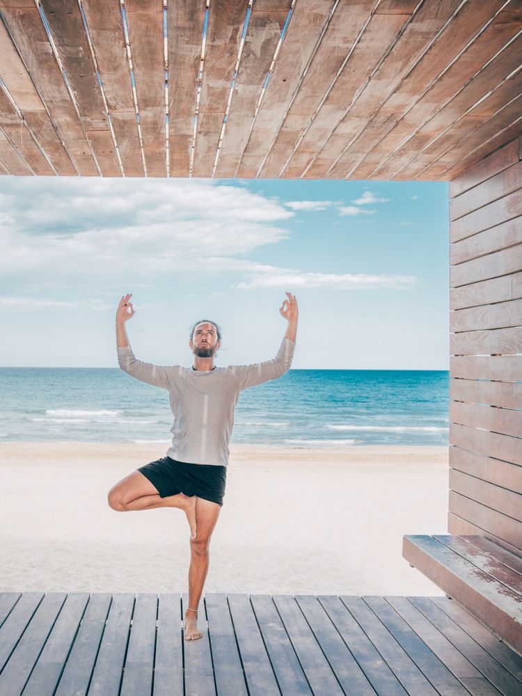 Man doing yoga by the beach