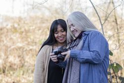 Two happy women review images from a photoshoot outdoors.