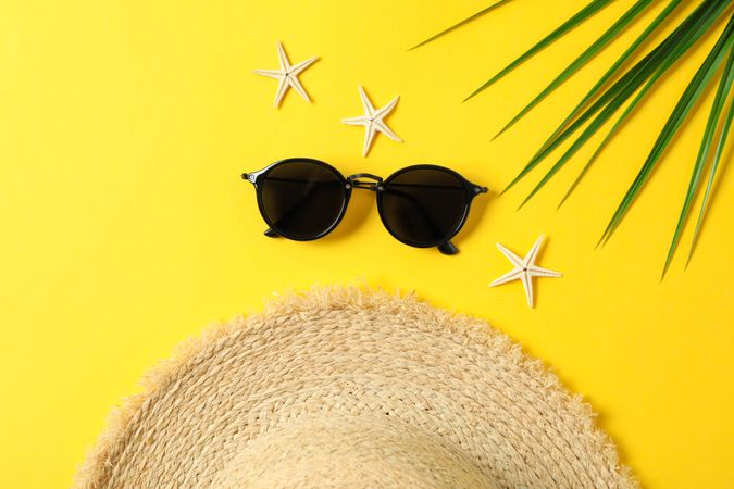 Straw hat, sunglasses, starfishes and palm leaf on color background space for text and top view. Summer vacation backdrop