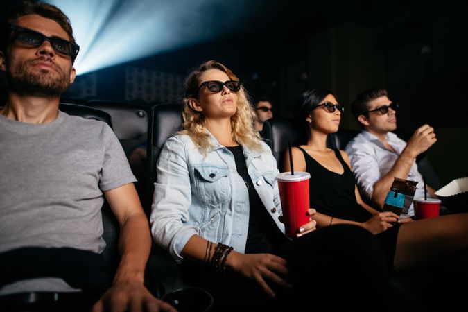 Men and women with drinks watching 3d film