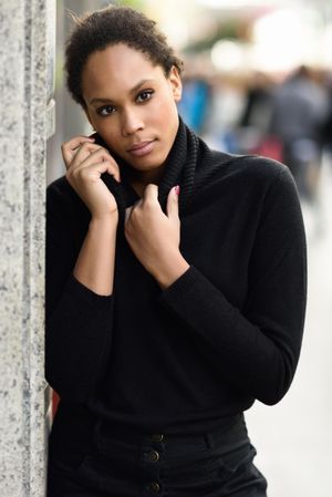 Serious woman holding neck of her dark sweater outside