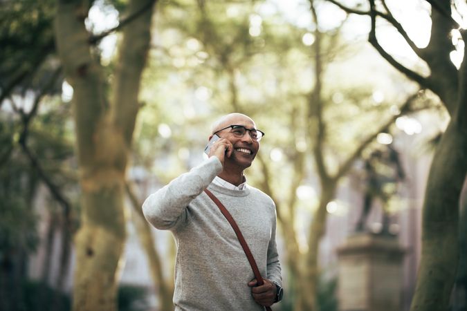 Smiling businessman talking over cell phone while walking outside