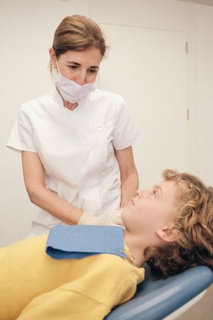 Dentist standing near boy on chair