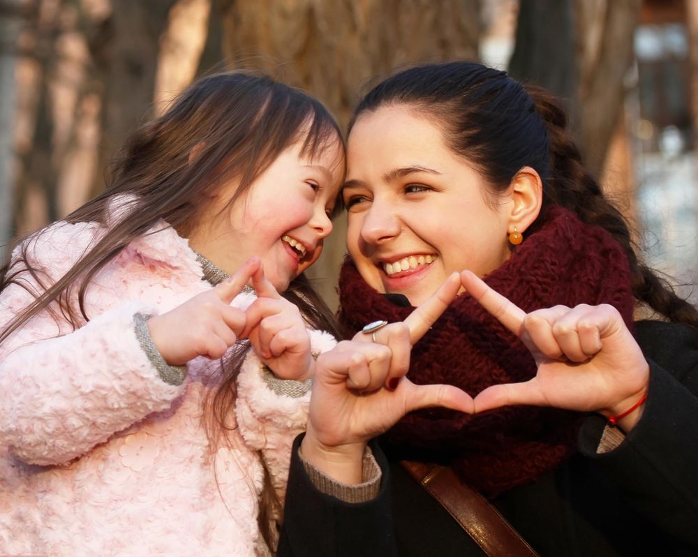 Two sisters laughing and smiling together outside on a cold day